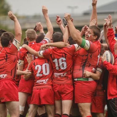 A group of men in rugby shirts are celebrating together
